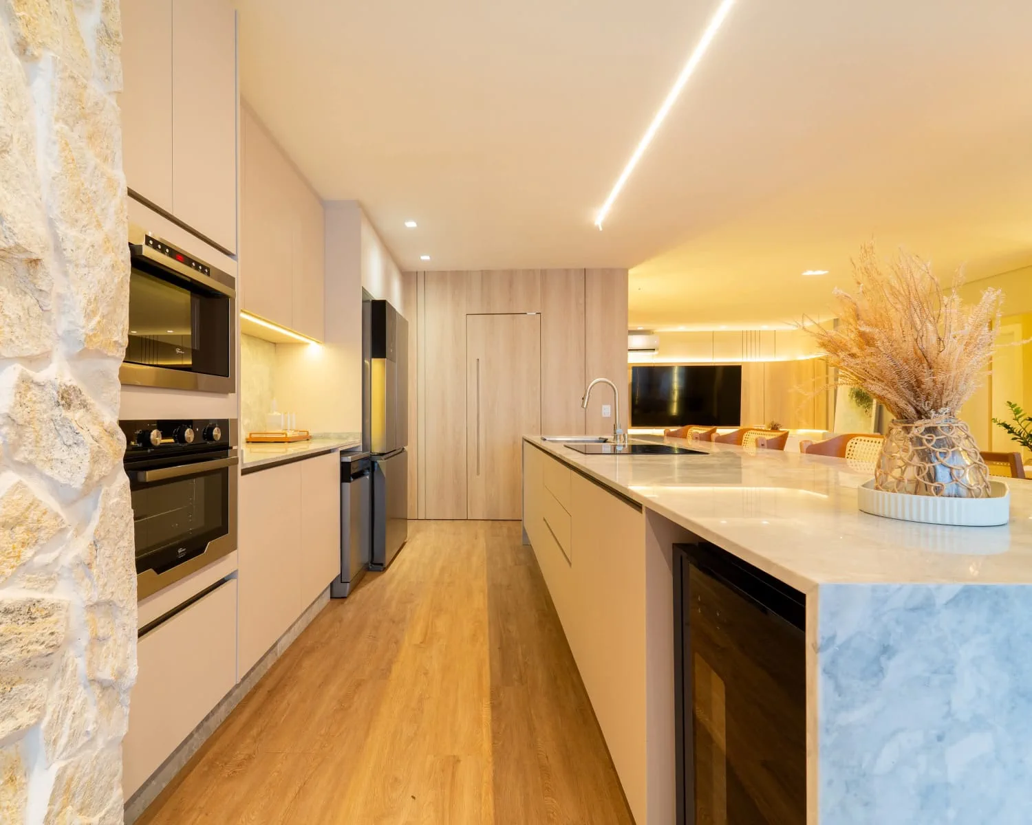 Cozinha planejada com ilha central, torre de eletros e integração com a sala