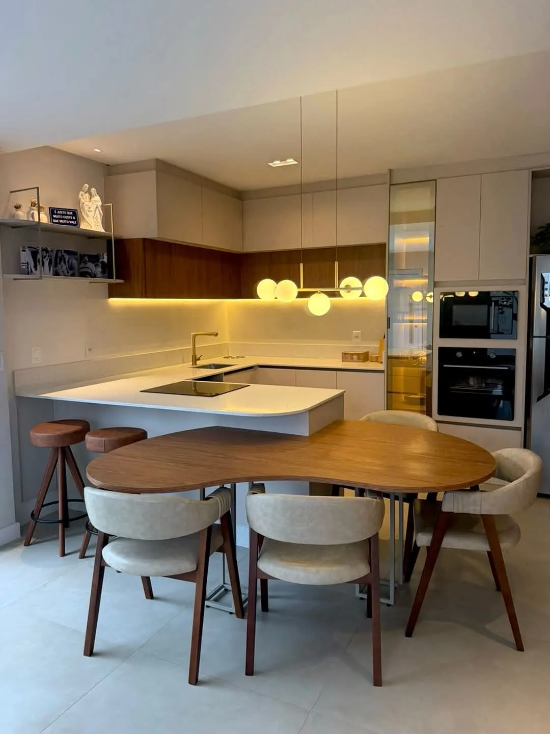 Cozinha planejada integrada à mesa de jantar com iluminação decorativa